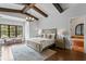 A stunning main bedroom has a tray ceiling with wood beams, neutral decor, and leads to an ensuite at 7713 Still Lakes Dr, Odessa, FL 33556
