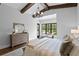 A stylish main bedroom has a tray ceiling with wood beams, neutral decor, and large windows overlooking the yard at 7713 Still Lakes Dr, Odessa, FL 33556