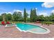 Beautiful pool and spa area with red lounge furniture, brick pavers, and greenery offering a luxurious outdoor retreat at 7713 Still Lakes Dr, Odessa, FL 33556