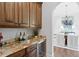 Elegant wet bar features granite countertops, custom cabinetry, and a wine cooler for sophisticated entertaining at 7713 Still Lakes Dr, Odessa, FL 33556