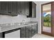 Stylish wet bar with granite countertop, dark wood cabinetry, mini fridge, and balcony access at 7713 Still Lakes Dr, Odessa, FL 33556