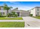 Charming single-story home featuring a two-car garage, palm trees, and landscaped front yard at 7725 Tangle Rush Dr, Gibsonton, FL 33534