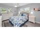 Cozy bedroom with neutral tones, two windows, and a large dresser with blue patterned bedding at 920 Virginia St # 109, Dunedin, FL 34698