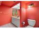 Red bathroom featuring tile floors, white vanity and toilet, accented with artwork at 9415 Blind Pass Rd # 1201, St Pete Beach, FL 33706