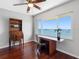 Cozy bedroom with rich hardwood floors, window view, and an antique secretary desk at 100 Bluff View Dr # 404C, Belleair Bluffs, FL 33770