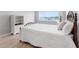 Bedroom with a water view features a wooden bed frame, white comforter, and wood flooring at 100 Bluff View Dr # 404C, Belleair Bluffs, FL 33770