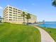 Beautiful waterfront condo building featuring lush lawn and tropical palms at 100 Bluff View Dr # 404C, Belleair Bluffs, FL 33770