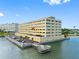An exterior view features waterfront property with a private pier and parking area next to a modern condominium complex at 100 Bluff View Dr # 404C, Belleair Bluffs, FL 33770