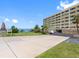 Lush landscaping in front of a multi-story tan building and parking area, sunny day at 100 Bluff View Dr # 404C, Belleair Bluffs, FL 33770
