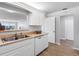 Modern kitchen with double sink, dishwasher, and white cabinets with easy access to an extra door and living room at 100 Bluff View Dr # 404C, Belleair Bluffs, FL 33770
