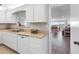 Modern kitchen features a double sink, dishwasher, white cabinets, and open layout that leads to the living room at 100 Bluff View Dr # 404C, Belleair Bluffs, FL 33770