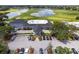 Aerial view of the clubhouse, parking lot, and manicured golf course with a beautiful pond at 1130 Hominy Hill Dr, Trinity, FL 34655