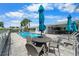 Relaxing pool area with patio tables, chairs, umbrellas, and lounge chairs with a clear blue sky at 1130 Hominy Hill Dr, Trinity, FL 34655