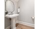 Bathroom with a pedestal sink, silver trimmed mirror and wood floors at 12 Country Club Ln, Belleair, FL 33756