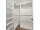Walk-in closet with white shelving and railing system, and wood floors at 12 Country Club Ln, Belleair, FL 33756