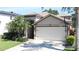 Charming home featuring a well-manicured lawn, mature palm trees, a driveway and an attached two-car garage at 12808 Killarney Ct, Odessa, FL 33556