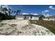 A single-story house sits on a property undergoing landscaping work, surrounded by a mix of sandy soil and fresh grass at 13266 Drysdale Ave, Port Charlotte, FL 33981