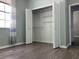 Bedroom with open bi-fold closet, light-colored walls, and wood-look flooring at 14510 Mj Rd, Myakka City, FL 34251