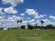 Wide shot of a home with green lawn, a shed, blue skies, and white puffy clouds at 14510 Mj Rd, Myakka City, FL 34251