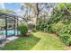 A lush backyard featuring a screened-in pool, green lawn and lots of shrubbery and shade at 15202 Heathridge Dr, Tampa, FL 33625