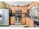 Kitchen with stainless steel appliances, wood cabinets, and a tiled backsplash, perfect for cooking enthusiasts at 15202 Heathridge Dr, Tampa, FL 33625