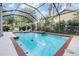 A large screened pool with brick trim surrounded by lush landscaping for privacy at 15202 Heathridge Dr, Tampa, FL 33625