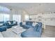 Bright living room featuring a blue sectional sofa, white drapes, and a view into the open kitchen at 1603 Scotch Pine Dr, Brandon, FL 33511