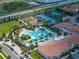 Aerial view of large community pool and clubhouse surrounded by palm trees and perfectly maintained landscaping at 17319 Holly Well Ave, Wimauma, FL 33598
