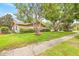 Exterior view of the home showcasing mature trees, lawn, and partial fencing at 1880 Oak Bark Ct, Clearwater, FL 33763