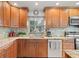Bright kitchen featuring granite countertops, stainless steel appliances, wooden cabinetry, and a tiled backsplash at 1880 Oak Bark Ct, Clearwater, FL 33763