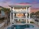 Three-story beach house with a pool, spa, and multiple balconies at sunset at 2 Gulf Blvd, Indian Rocks Beach, FL 33785