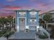 Stunning two-story blue home with white trim, balconies, a paved driveway, and tropical landscaping at 2 Gulf Blvd, Indian Rocks Beach, FL 33785