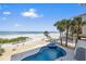 Backyard beach and pool area with beach views, palm trees and a privacy fence at 2 Gulf Blvd, Indian Rocks Beach, FL 33785