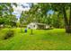 Sprawling backyard featuring lush green grass, mature trees, and a charming single-story home at 25623 Inkwood Pl, Wesley Chapel, FL 33544