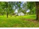 Lush backyard featuring green grass and mature trees surrounding a single-story home at 25623 Inkwood Pl, Wesley Chapel, FL 33544