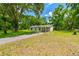 Single-story home with a covered carport and a long driveway, surrounded by mature trees at 25623 Inkwood Pl, Wesley Chapel, FL 33544