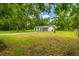 Scenic view of a single-story home surrounded by mature trees and expansive green lawn at 25623 Inkwood Pl, Wesley Chapel, FL 33544