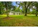 Charming single story home with a covered carport, nestled among mature trees and lush greenery at 25623 Inkwood Pl, Wesley Chapel, FL 33544
