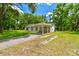Charming home with a covered carport and inviting driveway, surrounded by lush greenery at 25623 Inkwood Pl, Wesley Chapel, FL 33544