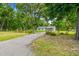 Gated entry leads to a well-maintained home with lush landscaping and mature trees at 25623 Inkwood Pl, Wesley Chapel, FL 33544