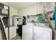 Functional laundry room with modern washer and dryer units and storage shelves at 25623 Inkwood Pl, Wesley Chapel, FL 33544