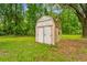 Exterior view of a weathered shed with double doors, surrounded by mature trees and greenery at 25623 Inkwood Pl, Wesley Chapel, FL 33544