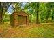 Exterior view of an outdoor shed with a roll-up door surrounded by mature trees and lush foliage at 25623 Inkwood Pl, Wesley Chapel, FL 33544