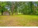 Backyard with storage sheds surrounded by mature trees and a verdant lawn at 25623 Inkwood Pl, Wesley Chapel, FL 33544
