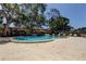 This image shows a community pool surrounded by lounge chairs and shaded by mature trees at 2932 Lichen Ln # D, Clearwater, FL 33760