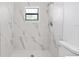 Bathroom with a window in the shower area, features white marble tile throughout at 4208 W Flora St, Tampa, FL 33614