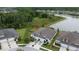 Aerial view of the home's driveway, landscaping, roof, and proximity to a wooded area and lake at 4583 Barletta Ct, Wesley Chapel, FL 33543