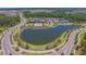 An aerial perspective of community amenities, featuring a lake, clubhouse, pool, and tennis courts at 4583 Barletta Ct, Wesley Chapel, FL 33543