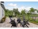 Paver patio with a fire pit, chairs, grill and view of the fenced backyard and surrounding trees at 4583 Barletta Ct, Wesley Chapel, FL 33543