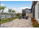Paver patio with a fire pit, chairs, grill and view of the fenced backyard and lake at 4583 Barletta Ct, Wesley Chapel, FL 33543